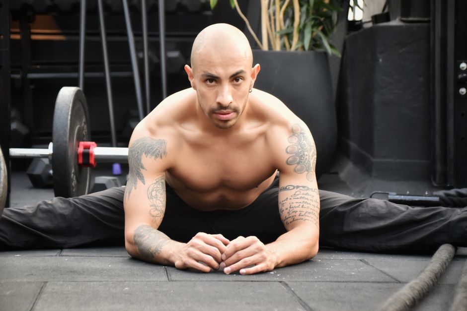 Homem realizando alongamento ou exercício de flexibilidade no ambiente de academia, focado em mobilidade e condicionamento físico.