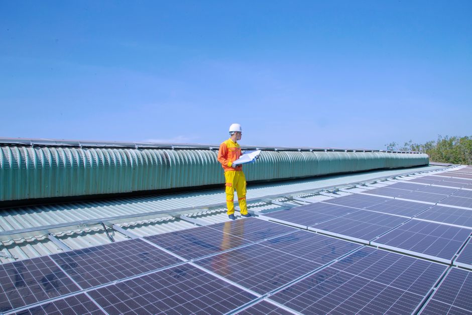 Profissional técnico avaliando painéis solares em uma instalação fotovoltaica ao ar livre, destacando o setor de energia sustentável.