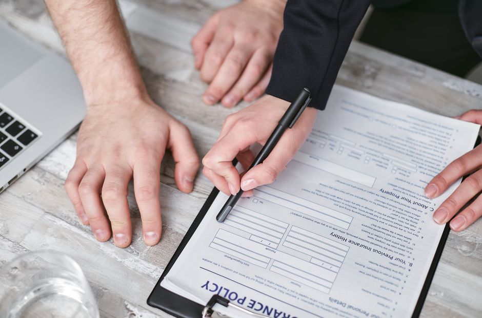 Duas pessoas revisando e assinando um contrato de franquia em uma mesa de madeira, simbolizando negociação comercial ou parceria empresarial.