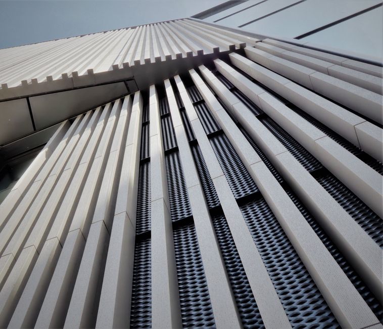 Imagem de uma fachada moderna de edifício com detalhes arquitetônicos em linhas verticais e detalhes em metal, destacando inovação em design urbano.