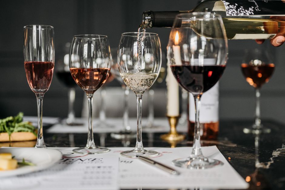 Imagem de taças de vinho sendo servidas em uma ocasião de celebração ou confraternização.