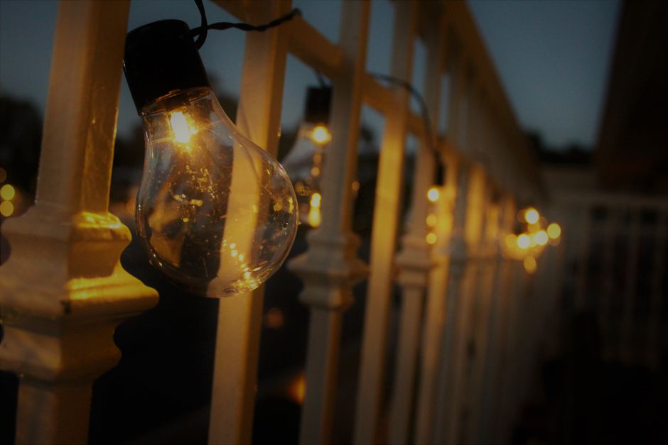 Foto de luzes decorativas em uma ponte ou varanda durante o entardecer, criando um ambiente acolhedor e artístico.