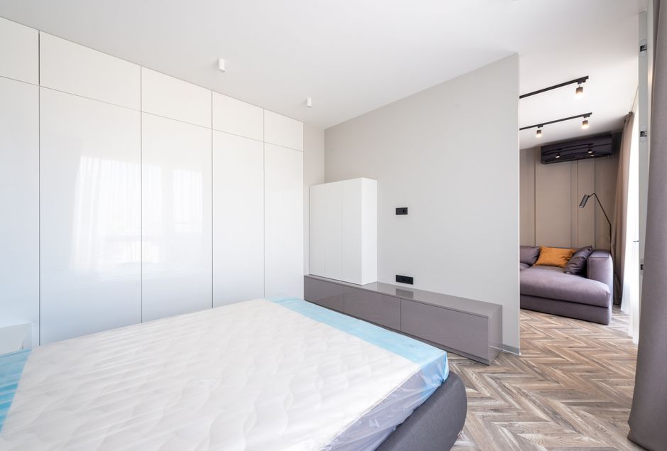 Sala moderna com quarto e área de descanso integrada, destacando o design minimalista e funcionalidade do espaço.
