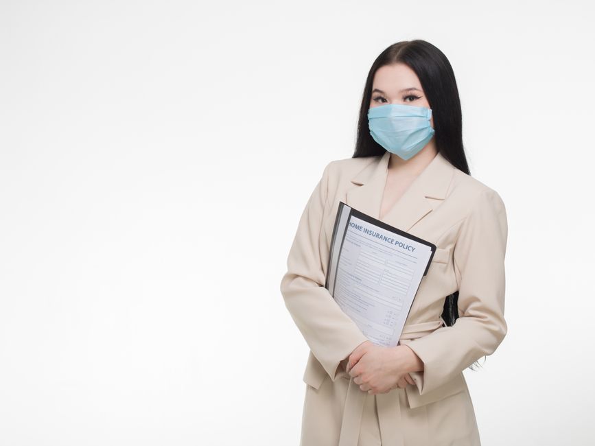 Mulher segurando um documento de apólice de seguro residencial enquanto usa máscara facial, simbolizando cuidados na contratação de serviços de proteção.