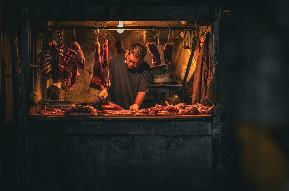 Homem preparando carne em uma churrasqueira ao ar livre, com atmosfera aconchegante e iluminação quente.