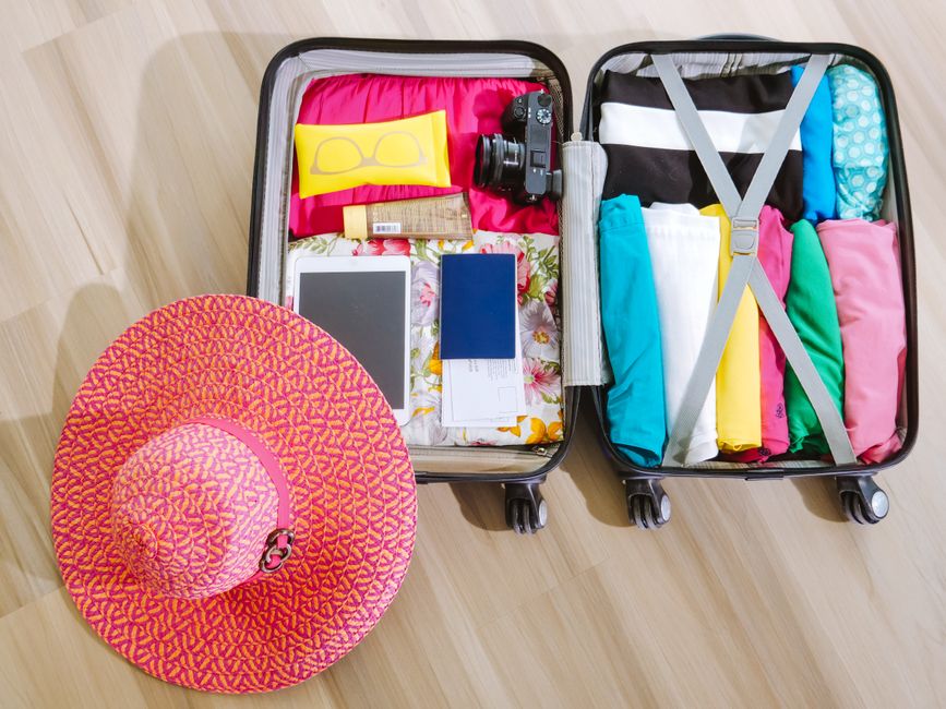 Pacote de roupas e acessórios preparado para viagem, com destaque para itens de verão e equipamentos de lazer.