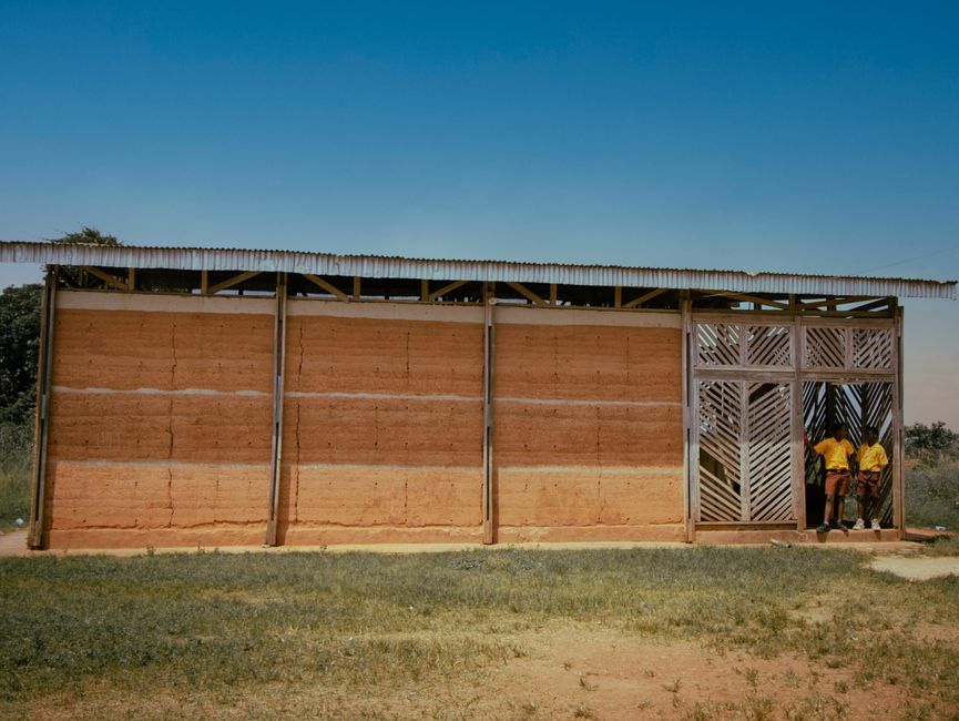 Construção de uma escola ou sala de aula em uma área rural, destacando o desenvolvimento educacional em comunidades distantes.