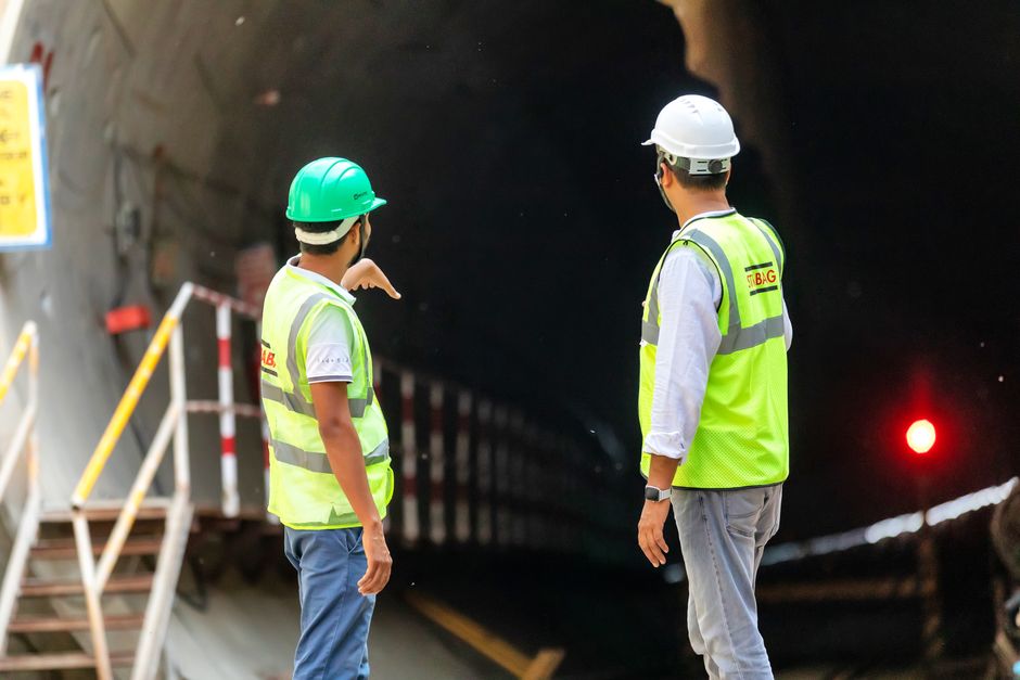 Engenheiros supervisionando uma obra dentro de um túnel, discutindo o progresso e as próximas etapas do projeto de infraestrutura.