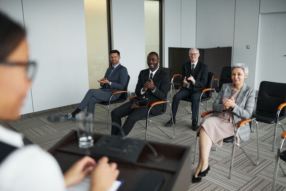 Grupo de profissionais participando de uma reunião de negócios em ambiente corporativo formal.