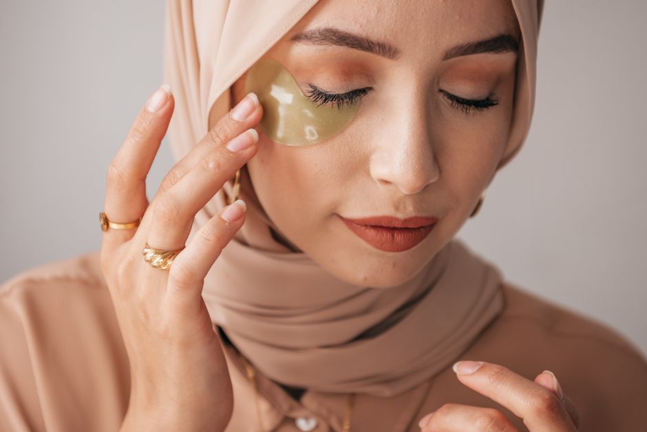 Mulher aplicando máscara facial com olhos fechados, demonstrando rotina de skincare e cuidados com a pele.