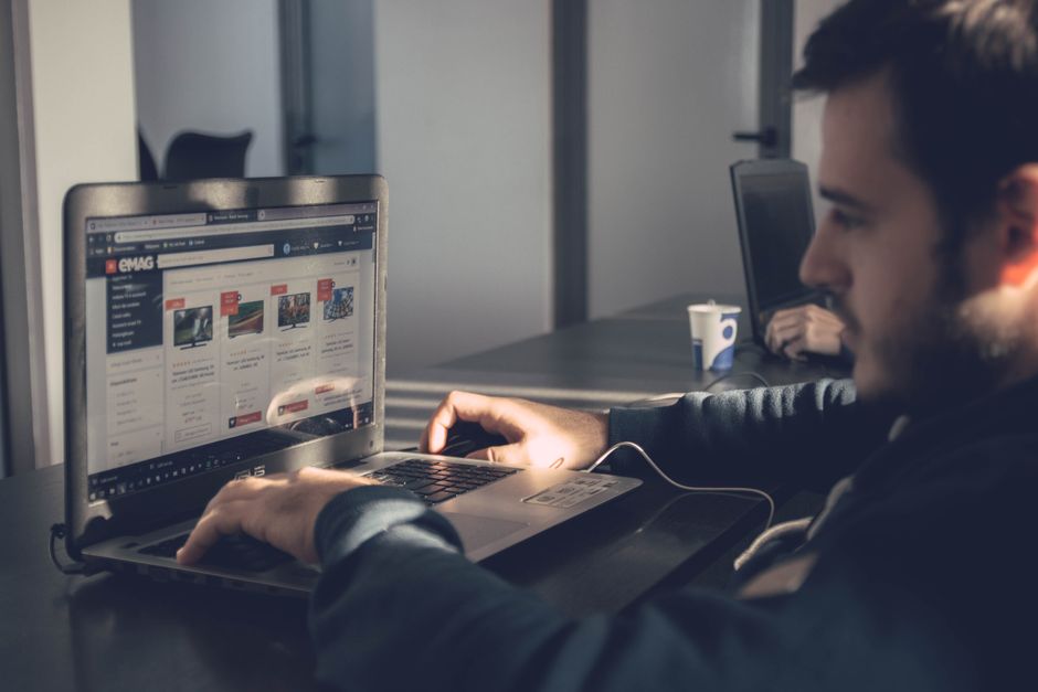 Homem utilizando computador em um ambiente de trabalho, focado em atividades digitais e conexão online.