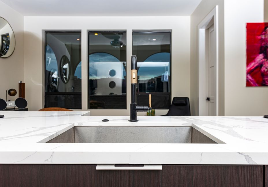 Imagem de uma cozinha moderna com uma pia de design minimalista e janelas amplas ao fundo, destacando o ambiente sofisticado e funcional.