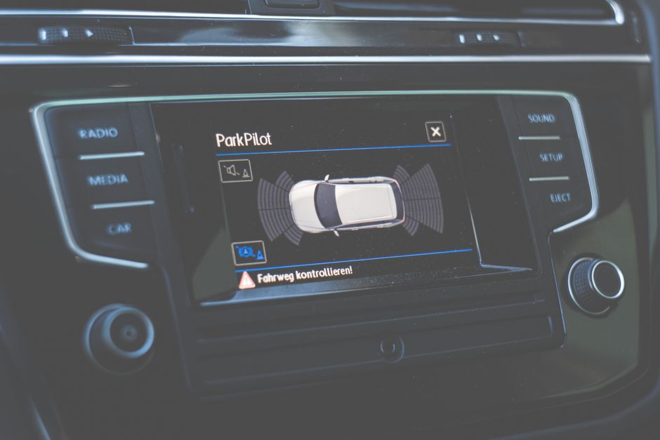 Tela de sistema de estacionamento com monitoramento de sensores e controle de assistente de volante em um carro moderno.