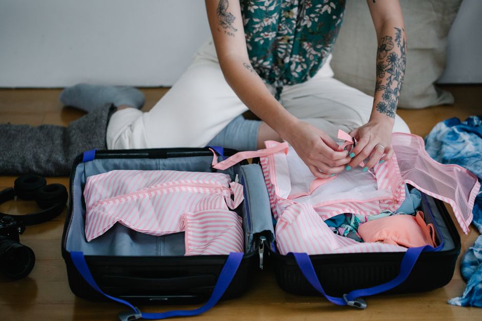 Pessoa organizando roupas em mala, preparando-se para uma viagem de lazer ou férias.