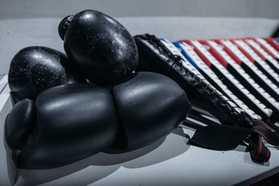 Par de luvas de boxe e protetor bucal utilizados em treinamentos de esporte de combate, sobre uma superfície plana.