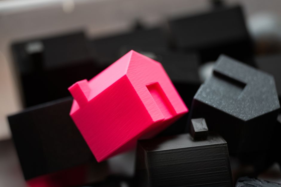 Imagem de objetos decorativos em formato de casas em cores vibrantes, usados como símbolo de imobiliário ou moradia em conteúdo de blog sobre imóveis e arquitetura.