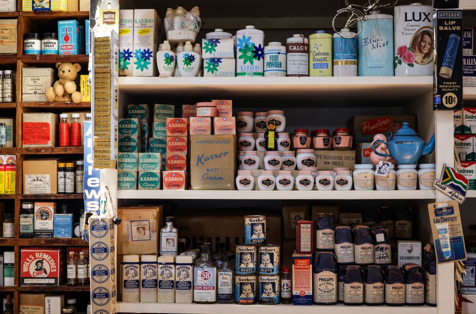 Imagem de uma prateleira cheia de produtos farmacêuticos e de saúde em uma farmácia, destacando a variedade de medicamentos e cosméticos disponíveis.