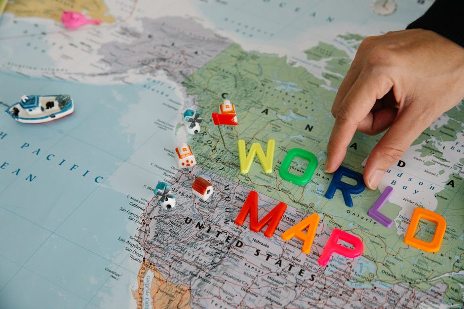 Imagem ilustrando a importância do trabalho e da colaboração global nas organizações modernas, usando um mapa-múndi, letras coloridas e elementos de viagem.