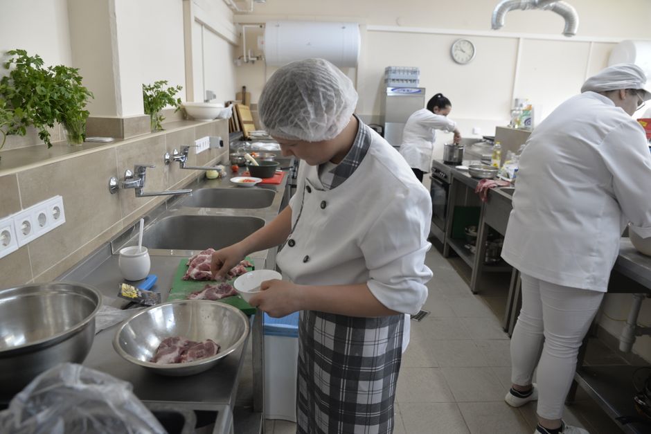 Juventude em aula prática de culinária, aprendendo técnicas de preparo de carnes em uma cozinha escolar ou profissional.