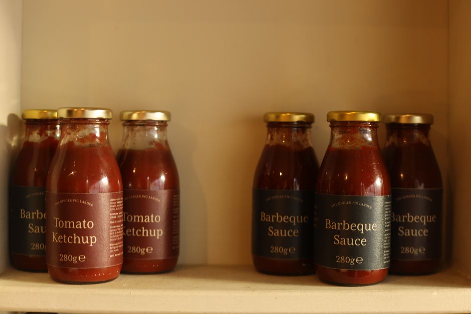 Imagem de potes de molho barbecue e ketchup na geladeira, destacando opções de condimentos para churrasco e gastronomia ao ar livre.