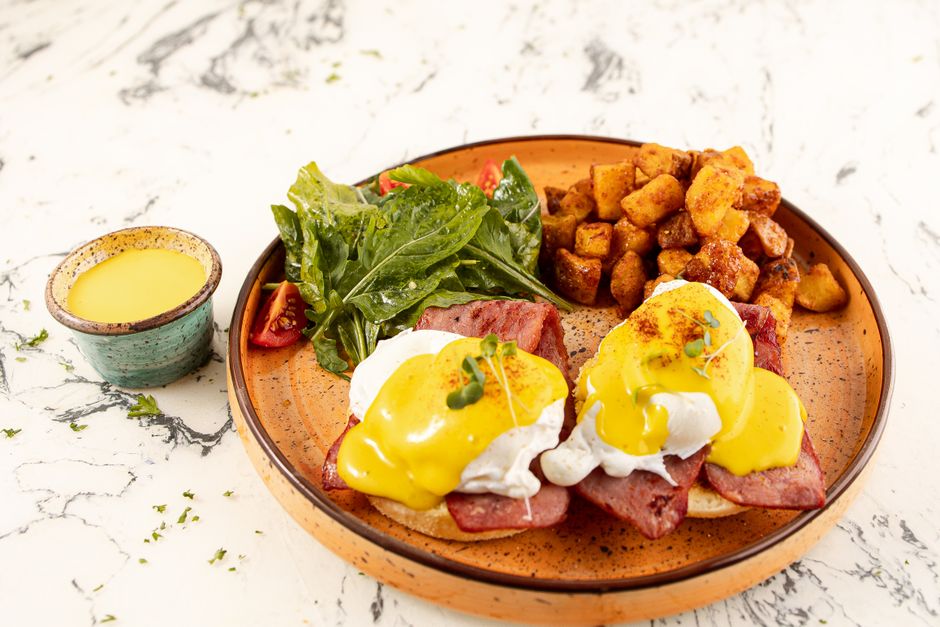 Imagem de um café da manhã com ovos beneditinos, batatas assadas e salada, ideal para ilustrar um artigo sobre brunch ou alimentação saudável.