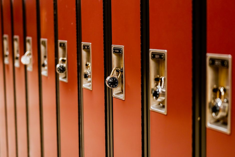 Imagem de várias portas de armários escolares fechadas, algumas com cadeados, simbolizando segurança e organização em ambiente educacional.
