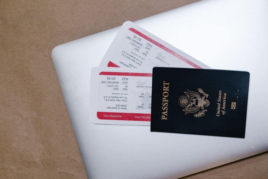 Imagem de passaporte e passagens aéreas sobre um laptop, ilustrando planejamento de viagem internacional.