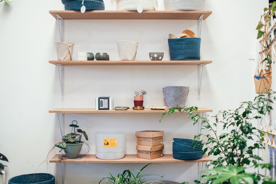Imagem de prateleiras de madeira decoradas com vasos, caixas e objetos de design, ideal para ilustrar ambientes de estética moderna e organização de espaços internos.