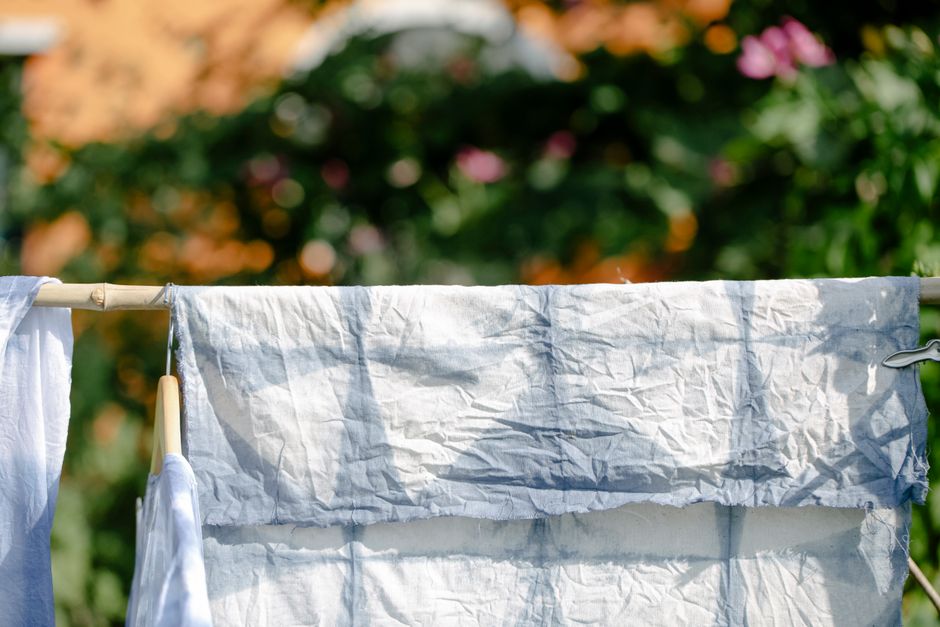 Telas brancas estendidas ao ar livre, simbolizando limpeza, sustentabilidade ou moda sustentável em um ambiente externo.