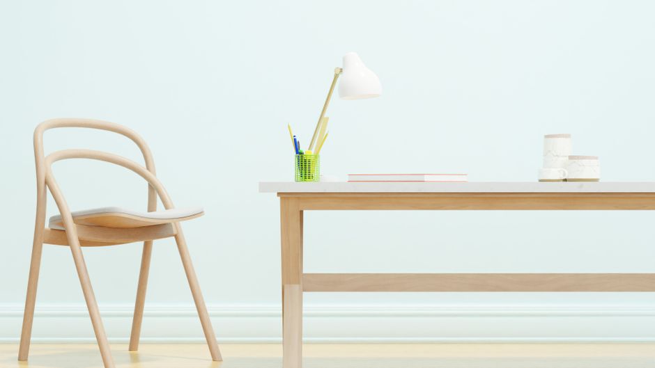 Imagem de um ambiente de trabalho minimalista com uma mesa de madeira, cadeira de design simples e objetos de escritório, transmitindo uma atmosfera de organização e produtividade.