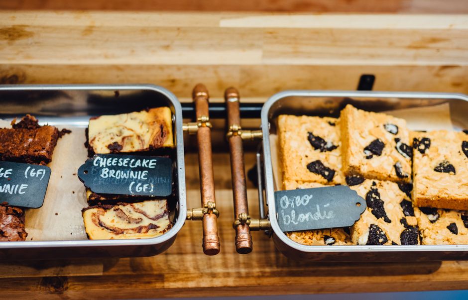 Tabela de brownies variados direcionada para degustação ou venda, com destaque para diferentes sabores em uma loja ou padaria artesanal.