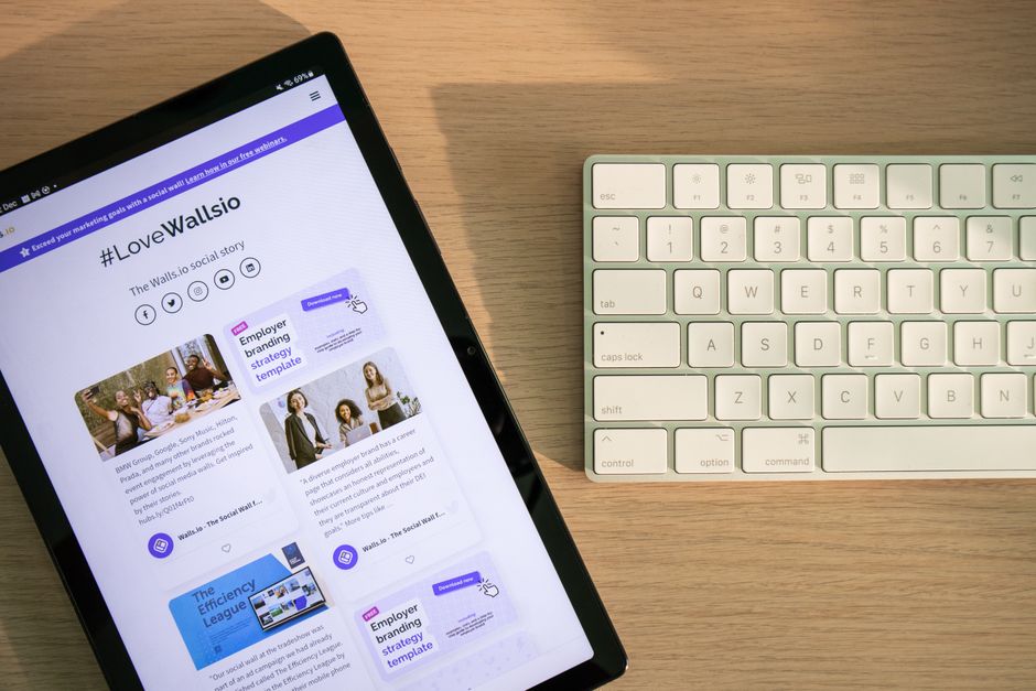 Imagem de um tablet exibindo conteúdo relacionado a estratégias de marketing digital ao lado de um teclado em uma superfície de madeira, ilustrando o tema de gestão de mídias sociais e produtividade no ambiente de trabalho.