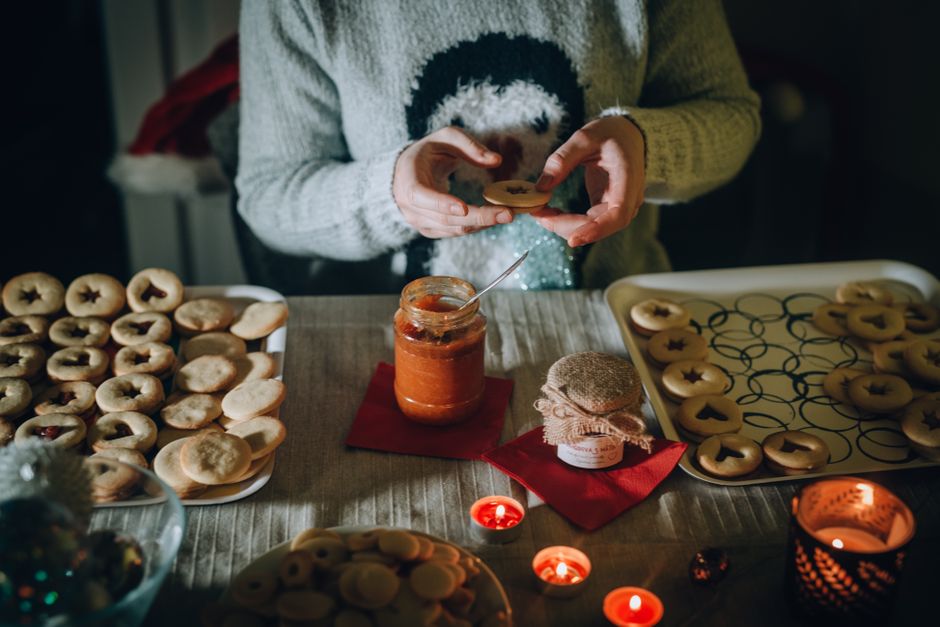 Pessoa preparando biscoitos decorativos em uma cozinha para ocasião festiva, com foco na atmosfera de comemoração.