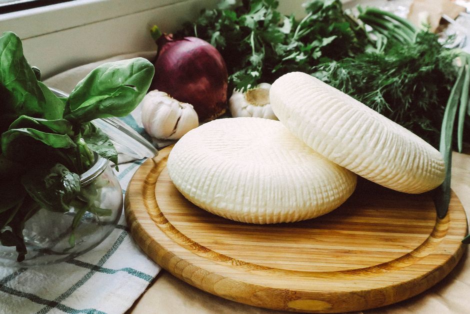 Queijo branco fresco ao lado de ingredientes naturais, ideal para receitas de culinária caseira e alimentação saudável.