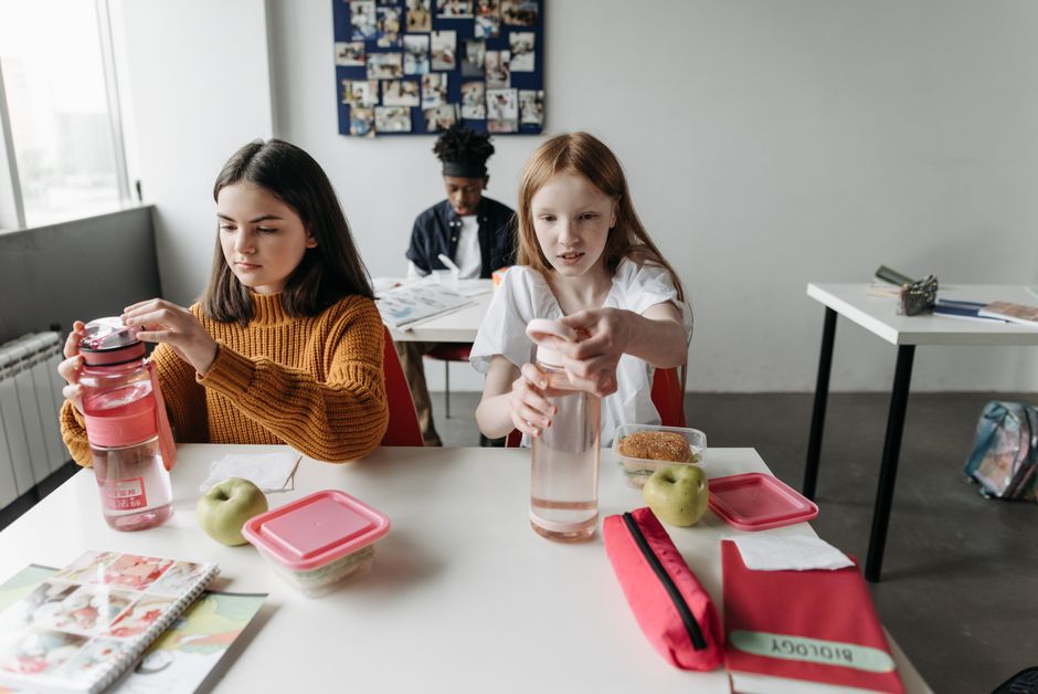 Crianças na sala de aula preparando suas refeições escolares com atenção e organização.