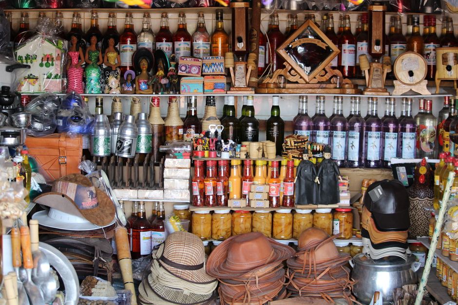 Vitrine de loja de artesanato com diversas bebidas, acessórios e objetos decorativos, destacando a variedade e o clima de comércio tradicional.