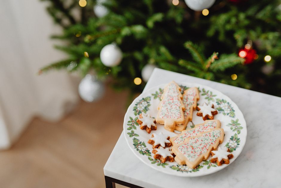 Cookies decoradas de Natal sobre uma tigela, com árvore de Natal ao fundo.