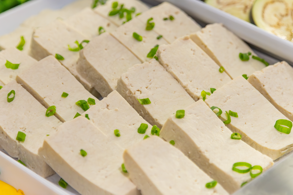 Carne de soja ou tofu cortada em cubos, decorada com cebolinhas verde-claras, apresentada em uma travessa, ideal para um artigo sobre opções vegetarianas e receitas saudáveis.