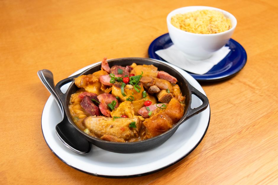 Imagem de uma porção de ensopado de batata-doce com carne, acompanhada de uma xícara de farofa, ideal para ilustrar receitas tradicionais brasileiras.