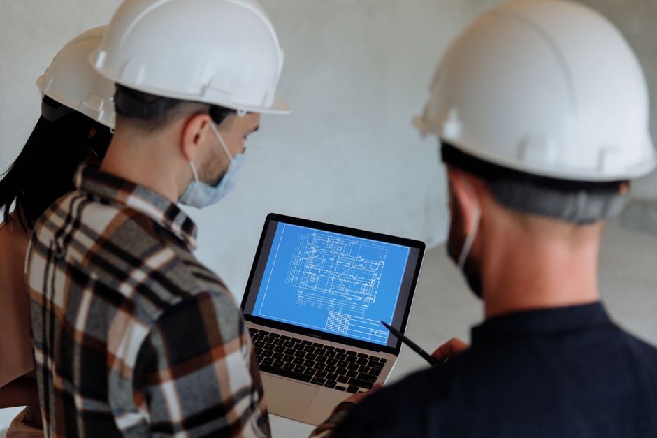 Engenheiros analisando um projeto técnico em um ambiente de construção ou escritório, com foco em planejamento e tecnologia na engenharia civil.