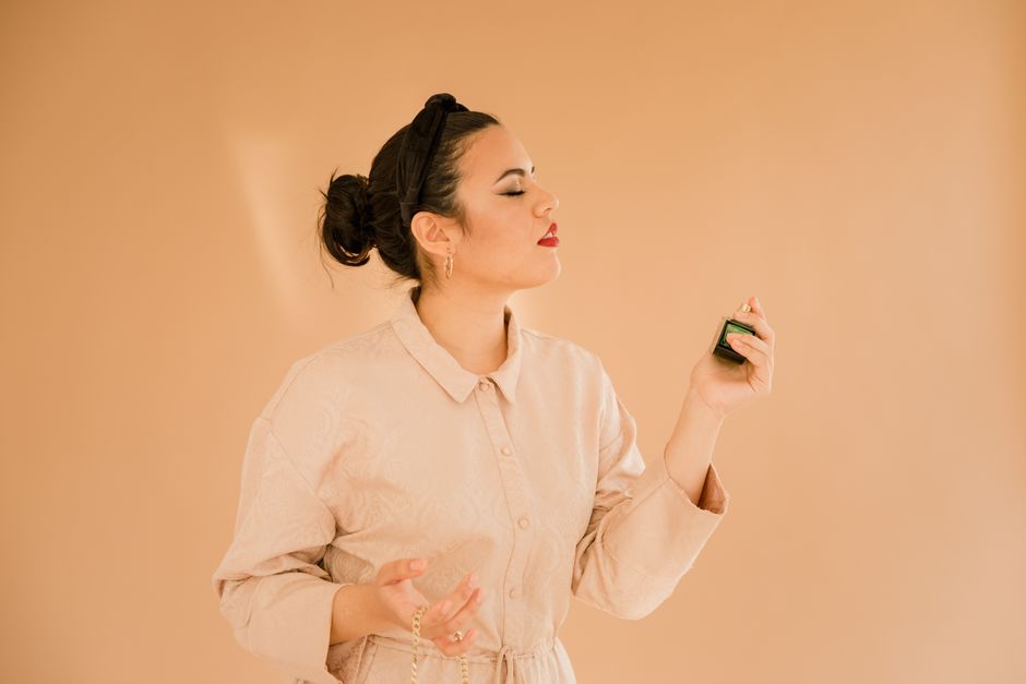 Mulher com expressão confiante, segurando um controle remoto, simbolizando controle ou decisão em um ambiente interno com fundo neutro.
