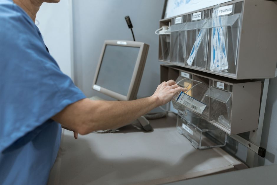 Profissional de saúde organizando materiais de escritório em ambiente clínico para ilustrar gestão de recursos hospitalares.