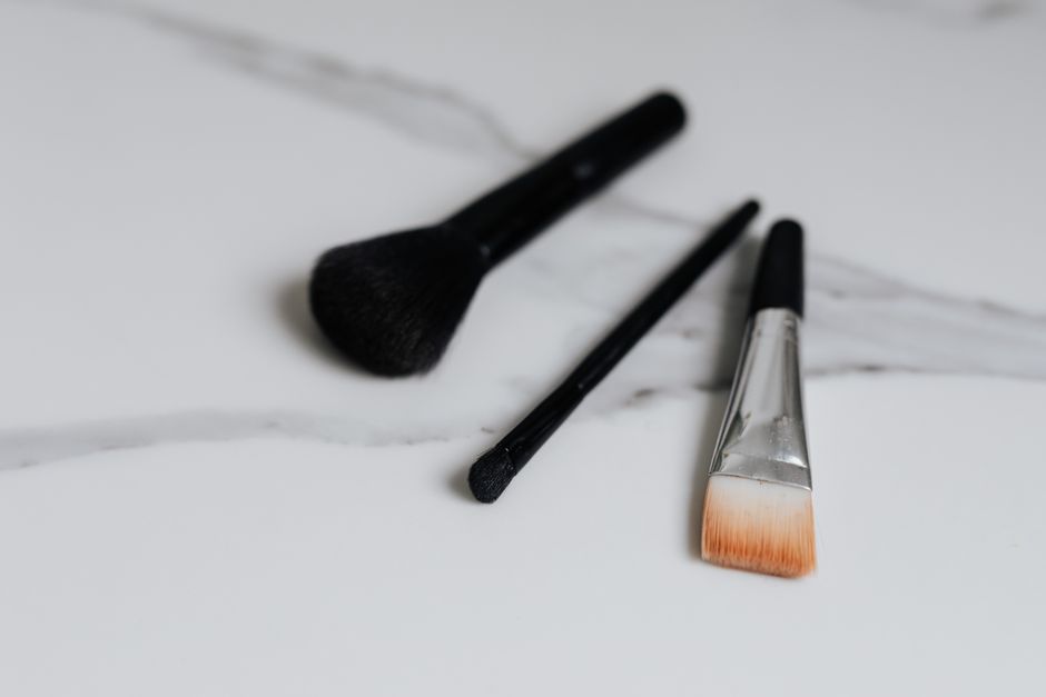 Imagem de três pinceis de maquiagem dispostos sobre uma superfície branca, ideal para ilustrar beleza e cuidados pessoais em um blog de estilo de vida.