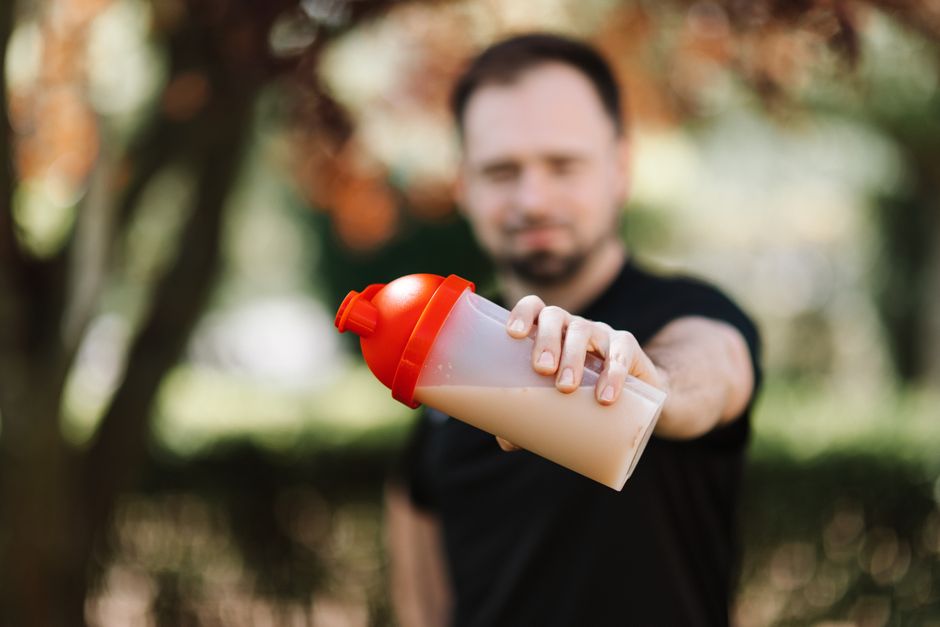 Homem segurando um pequeno cofre de exercício ao ar livre, simbolizando segurança, proteção ou economia.