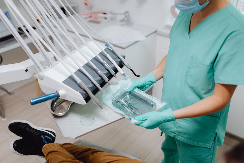 Profissional de saúde manipulando instrumentos odontológicos em uma clínica ou consultório, destacando o ambiente de atendimento clínico.