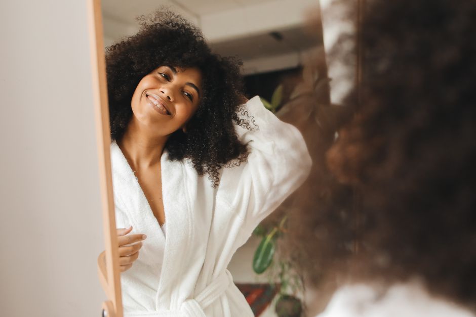 Mulher sorridente em um momento de autocuidado, refletindo bem-estar e autoestima.