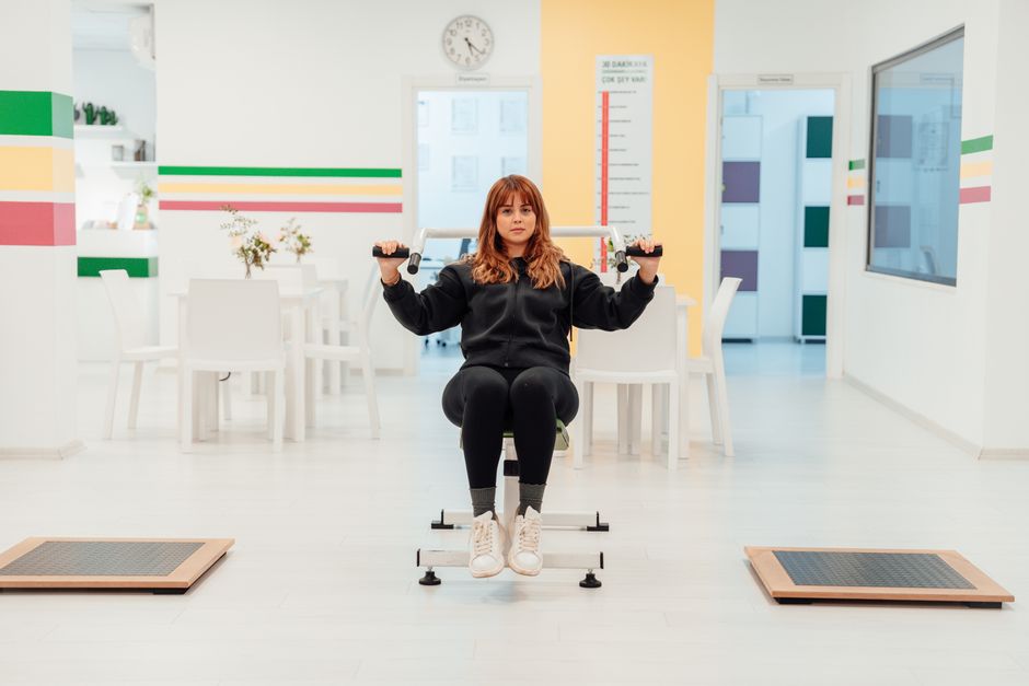 Mulher realizando exercícios físicos em ambiente de clínica ou espaço de bem-estar, focada na saúde e na atividade física.