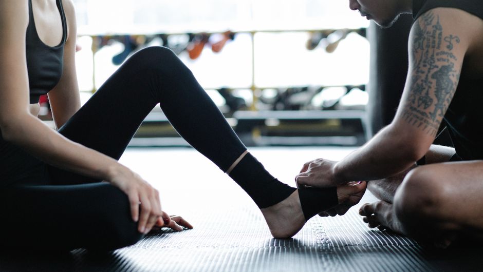 Pessoa recebendo assistência durante uma sessão de fisioterapia ou treino físico para recuperação ou melhora da mobilidade.