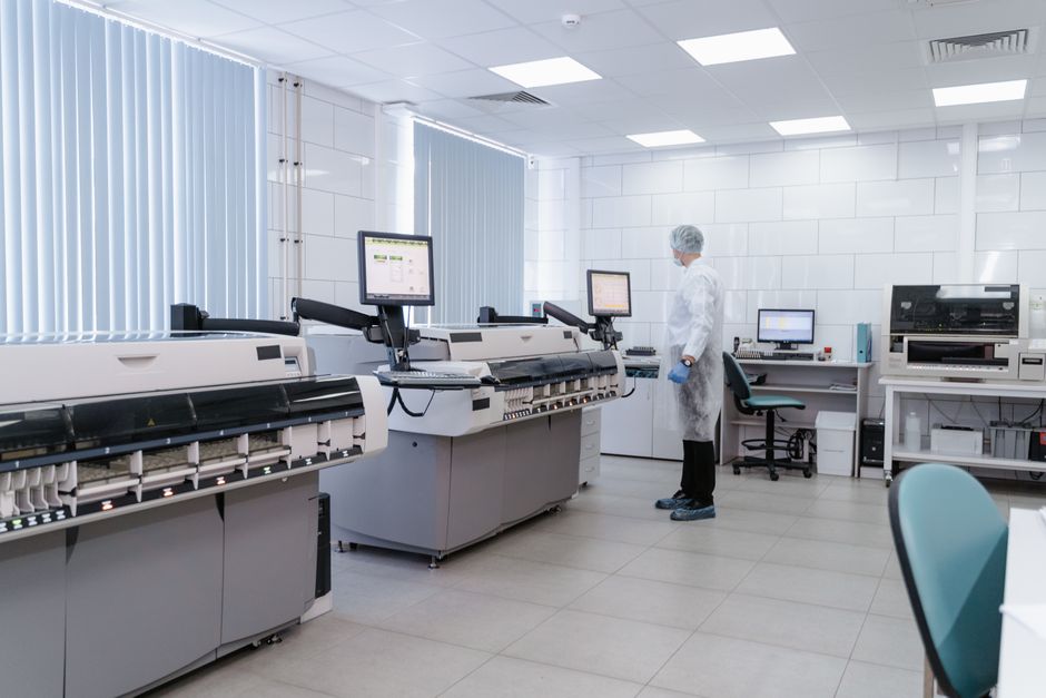Imagem de um laboratório de biotecnologia ou pesquisa científica, com equipamentos avançados e um profissional de jaleco realizando análises.
