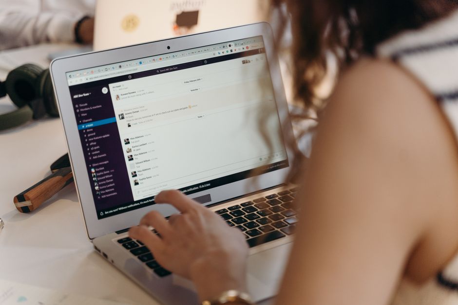Pessoa utilizando um computador portátil para comunicação ou trabalho, simbolizando produtividade e conexão digital.